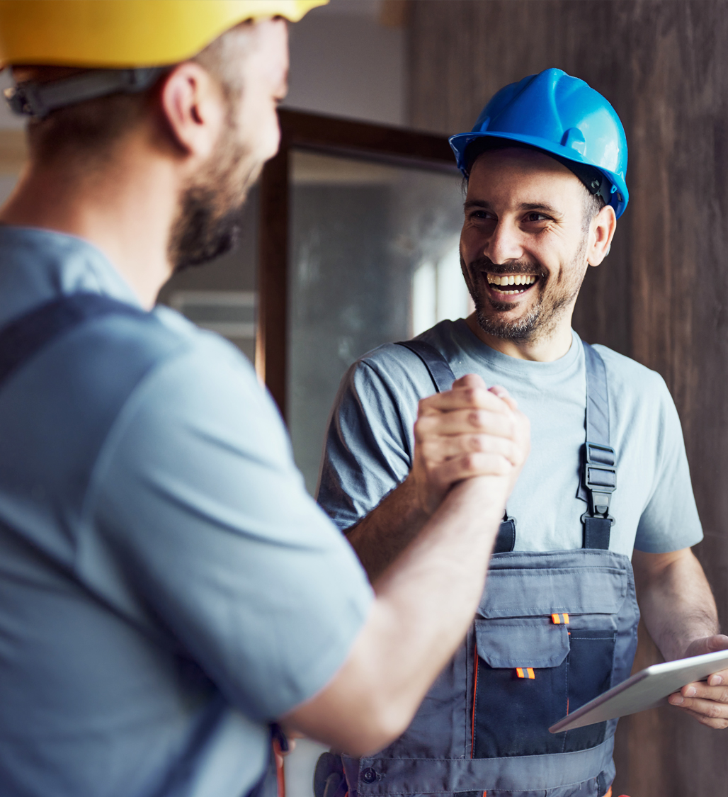 Zwei Handwerker mit Schutzhelmen geben sich Handschlag – Symbol für erfolgreiche Zusammenarbeit und digitale Projektlösungen über die directpool Plattform.